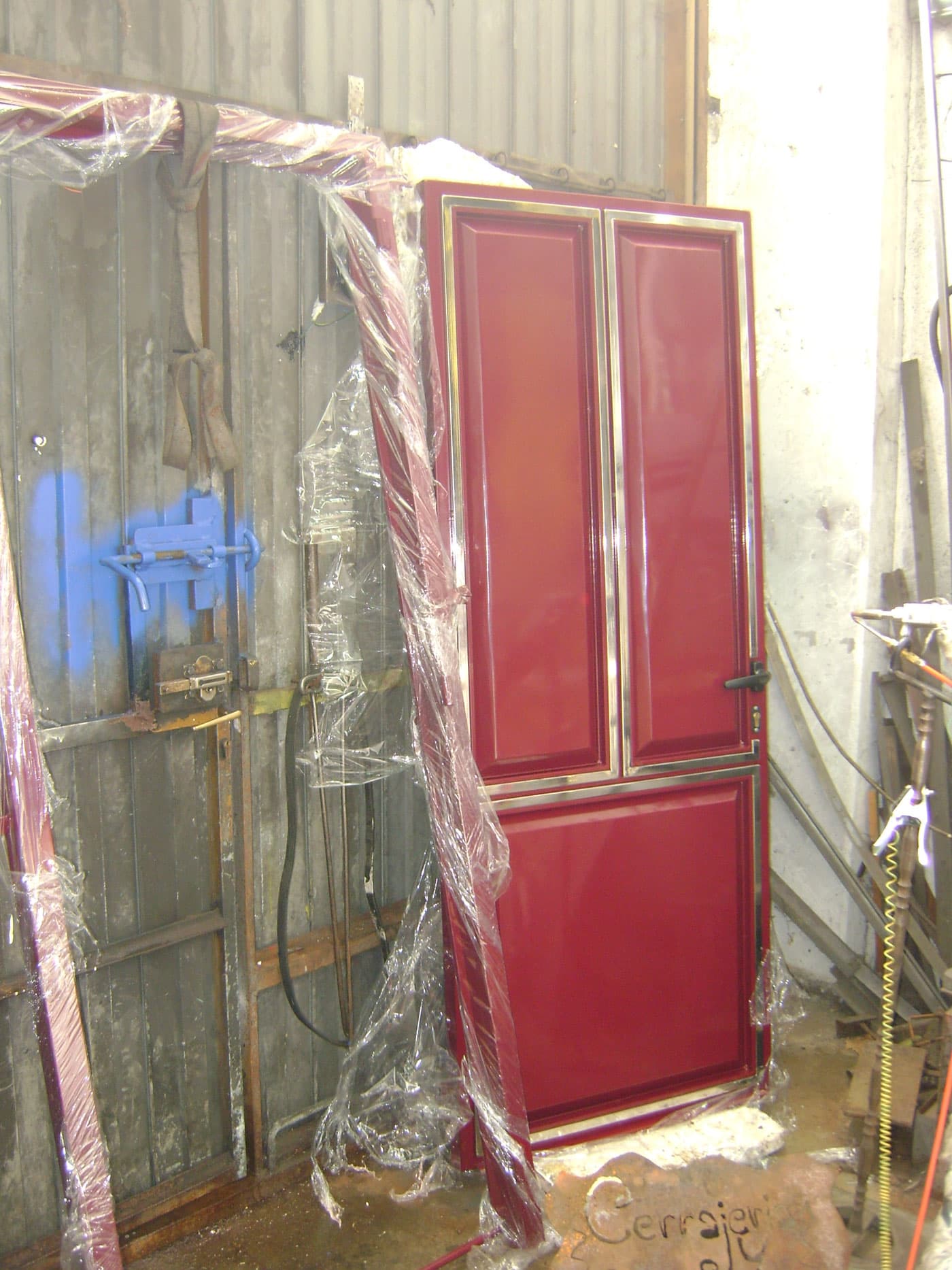 Puerta peatonal de tres cuarterones con embellecedores de inox 304, lacada en RAL 3005 y soldada con láser de fibra
